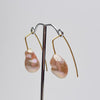 Pair of pearl earrings on a stand against a light gray background
