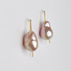 Pair of pearl earrings with gold hooks on a light gray background