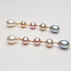 Five tier ombre pearl earrings with gold chain on a light gray background