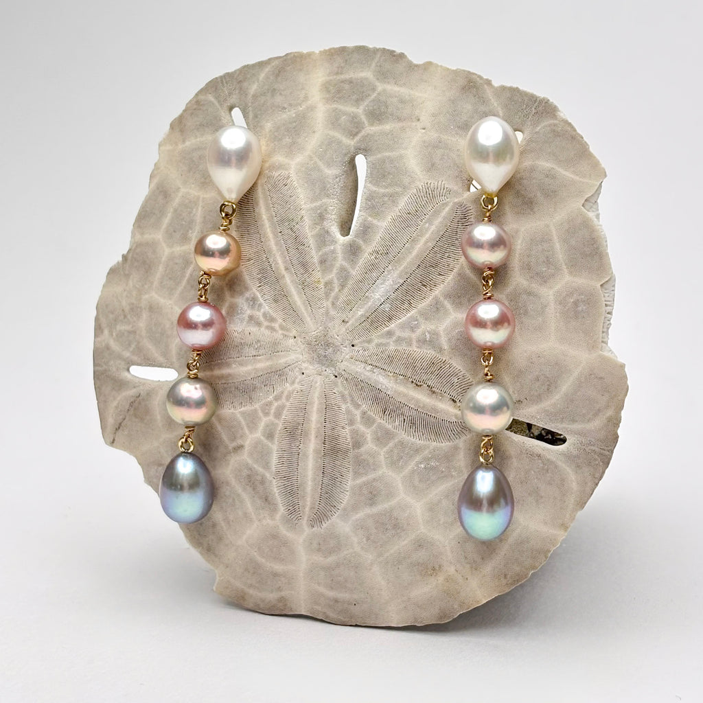 Five tier ombre pearl earrings on a sand dollar with a white background
