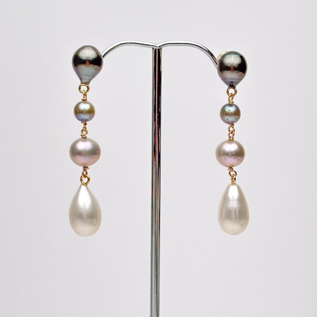 Pair of ombre pearl earrings on a stand against a white background