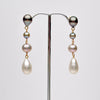 Pair of ombre pearl earrings on a stand against a white background