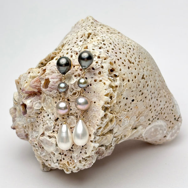 Multiple different color pearls set in 2" earrings  on a textured surface