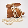 Wooden rabbit figurine with a pearl necklace on a white background
