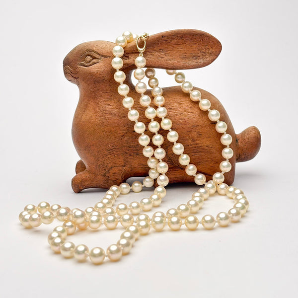 Wooden rabbit figurine with a pearl necklace on a white background