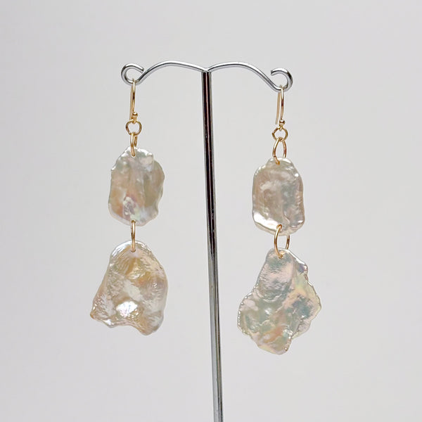 Pair of earrings with large, irregularly shaped high luster pearls on a gray background by kojima pearl