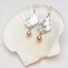 Pearl and gold drop earrings on a white shell  by kojima pearl